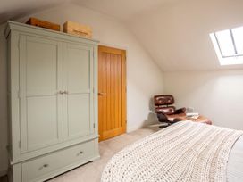 A bedroom with a wardrobe, armchair, and book at The Old Barn in Manchester