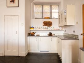 A kitchen with cabinets, sink, jars, and a window at The Old Barn in Manchester