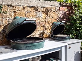 An outdoor kitchen with two grills and a stone wall at the property location