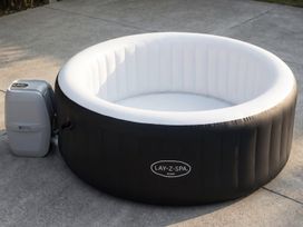 An inflatable hot tub with an attached pump in an outdoor area