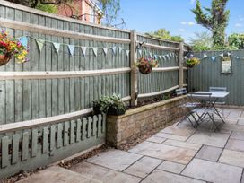 A garden with a patio, table, and hanging baskets at the property in 