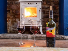 A living room with wine glasses and a bottle of red wine near a fireplace at The Old Barn in Manchester