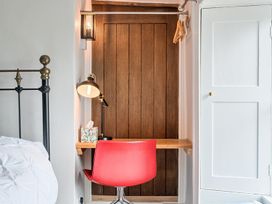 A bedroom with a red chair and a small table at Furzen Farmhouse