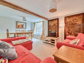 A living room with a dining table and TV at Furzen Farmhouse