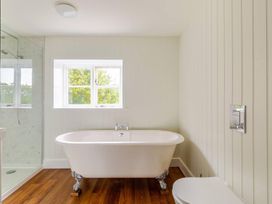 A bathroom with a bathtub and toilet at Furzen Farmhouse