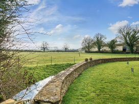 A field with trees and a stone wall at Furzen Farmhouse