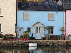 A house with table and chairs by the water at Quay Cottage in 