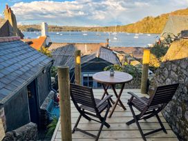 A balcony with two chairs and a table overlooking the sea at Quay Cottage