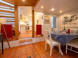 A dining room with a staircase and kitchen view at Quay Cottage