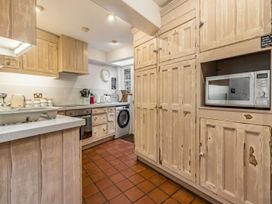 A kitchen with cabinets, microwave, oven and washing machine at Quay Cottage