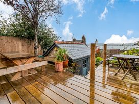 An outdoor area with wooden furniture and plants at Quay Cottage
