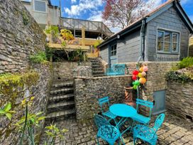 A garden with stairs leading to a small building and outdoor seating at Quay Cottage in 