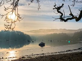 A scenic view of water with boats and tree branches at Quay Cottage
