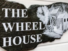 A stone sign with the text The Wheel House and an illustration of a watermill