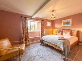 A bedroom with a bed, armchair, lamp, and window at The Old Barn in Manchester