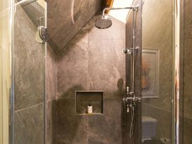 A shower with a shelf and a toilet in the bathroom