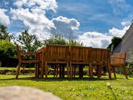 A wooden table with chairs in a garden with trees at 