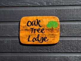 A wooden sign stating 'Oak Tree Lodge' with a tree illustration