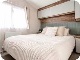 A bedroom with a large bed and shelves at Brookwood Willerby, 36 bay view, Filey
