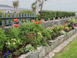 A garden with flowers and a stone wall at Wild Atlantic Way Country Cottage, Portmagee, County Kerry