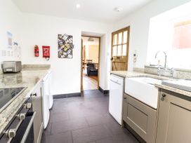 A kitchen with a toaster, dishwasher, sink, oven, and granite countertops at 3 Railway Cottages in Betws-y-Coed