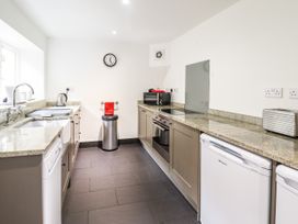 A kitchen with granite countertops appliances a sink and a trash can at 3 Railway Cottages Betws-y-Coed