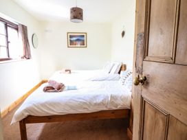 A bedroom with two single beds with towels on them a window on the left and a wooden door on the right at 3 Railway Cottages in Betws-y-Coed