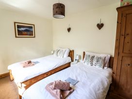 A bedroom with two single beds wooden furniture and folded towels at 3 Railway Cottages in Betws-y-Coed