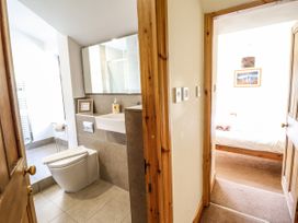 A bathroom with a toilet and sink next to a hallway leading to a bedroom with a bed and framed picture at 3 Railway Cottages in Betws-y-Coed