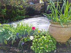 A garden with flowers and a stone patio at Llannor in Borth-y-Gest
