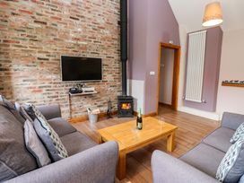 A living room with a sofa, coffee table, and television at Pottowe Cottage in Potto near Stokesley