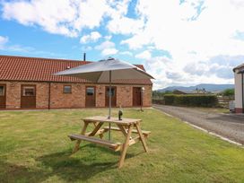 An outdoor area with a picnic table and umbrella at Pottowe Cottage Potto near Stokesley