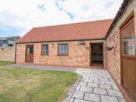An outdoor view of a cottage with brick walls and a door at Cooper Cottage Potto near Stokesley