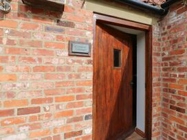 An entrance with a wooden door and brick wall at Cooper Cottage near Stokesley