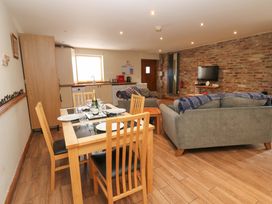 A living room and kitchen area with a dining table and sofa at Cooper Cottage Potto near Stokesley