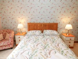 A bedroom with a bed and armchair at Cooper Cottage in Potto near Stokesley