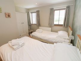 A bedroom with two beds and a wardrobe at Cooper Cottage Potto near Stokesley