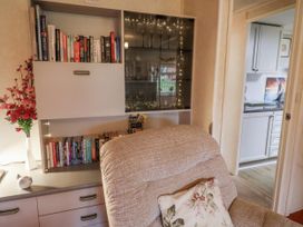 A living room with a bookshelf and armchair at The Lodge in Old Buckenham near Attleborough