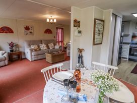 A living room with a sofa and dining area at The Lodge in Old Buckenham near Attleborough