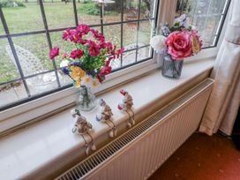 A living room with flowers and figurines on a windowsill at The Lodge Old Buckenham near Attleborough