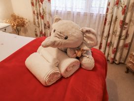 A teddy bear and rolled towels on a bed in The Lodge near Old Buckenham
