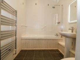 A bathroom with a bathtub, sink, and towel rail at Maritime Mews, 6 The Oakleys Porthmadog