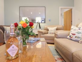 A living room with a coffee table and floral arrangement at Maritime Mews, 6 The Oakleys, Porthmadog
