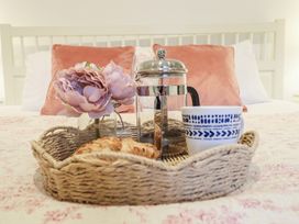 A tray with a coffee maker, cup, flower, and croissant on a bed at Maritime Mews, 6 The Oakleys, Porthmadog