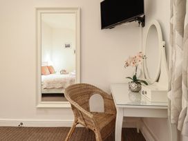 A bedroom with a chair, mirror, and television at Maritime Mews, 6 The Oakleys, Porthmadog