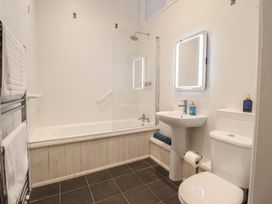 A bathroom with a shower over a bathtub and a wash basin at Maritime Mews, 6 The Oakleys, Porthmadog