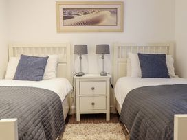 A bedroom with two beds and a nightstand at Maritime Mews, 6 The Oakleys in Porthmadog