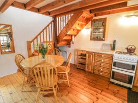 A kitchen and dining area with a wooden round table and four chairs near stairs at Arfron Penrhyddion Pella in Capel Garmon near Betws-y-Coed