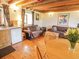 A living room with two sofas a wooden dining table with flowers and exposed wooden ceiling beams at Arfron Penrhyddion Pella in Capel Garmon near Betws-y-Coed