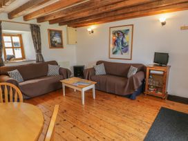 A living room with two sofas a wooden coffee table a small TV on a cabinet and exposed wooden ceiling beams at Arfron Penrhyddion Pella in Capel Garmon near Betws y Coed
